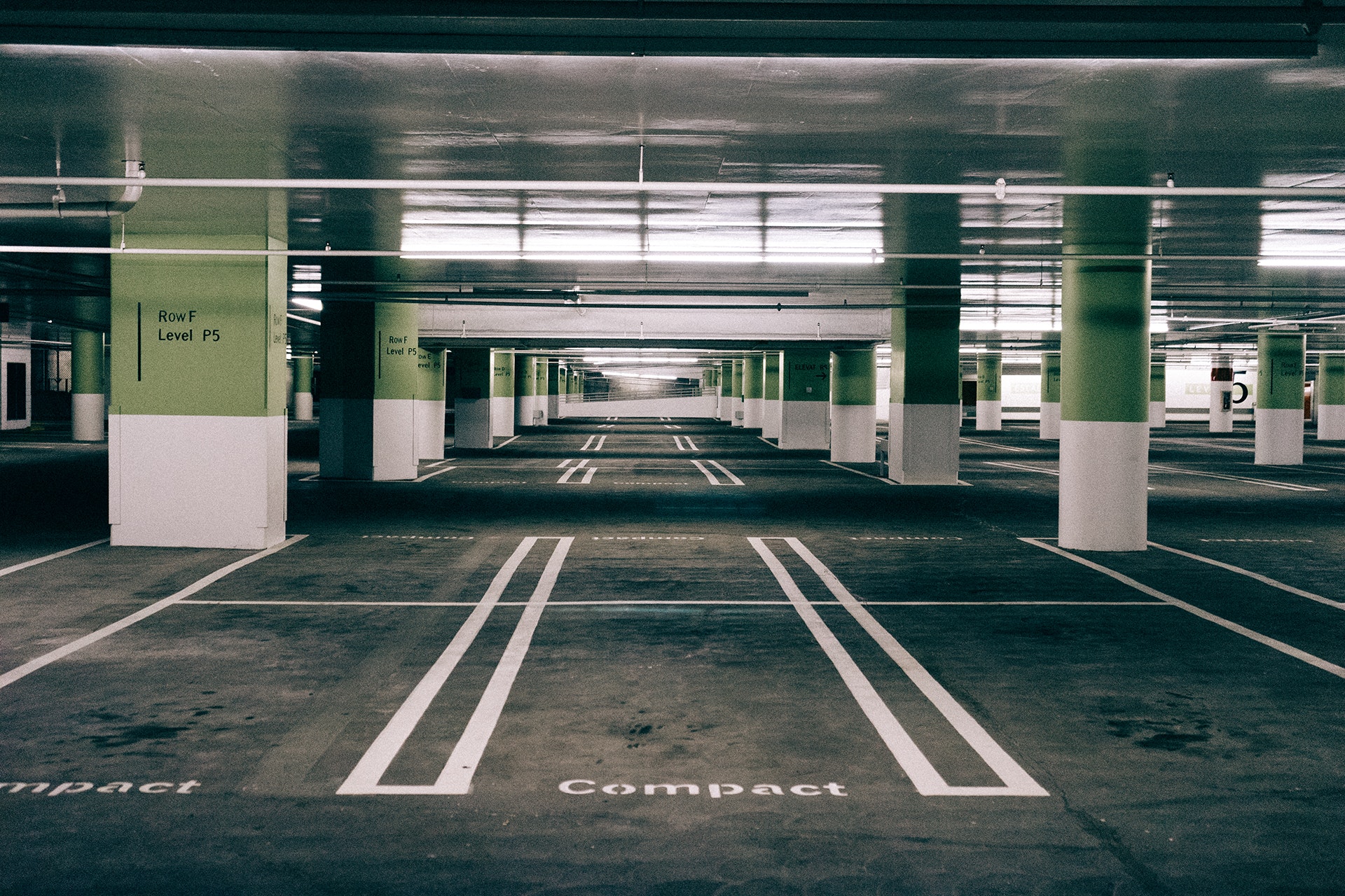 An empty, well-lit underground parking garage with rows of defined parking spaces marked 