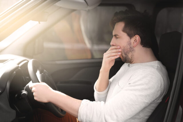 fatigued driving motorist yawning behind wheel